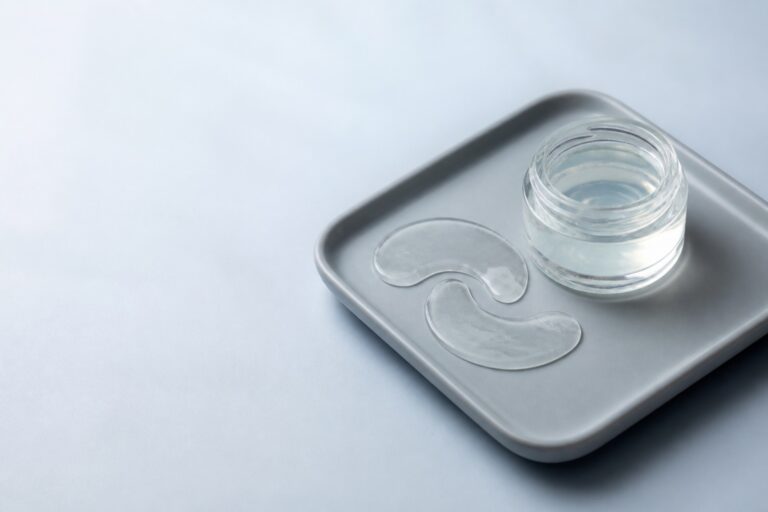 Under-eye gel patches on a ceramic tray beside a small glass jar